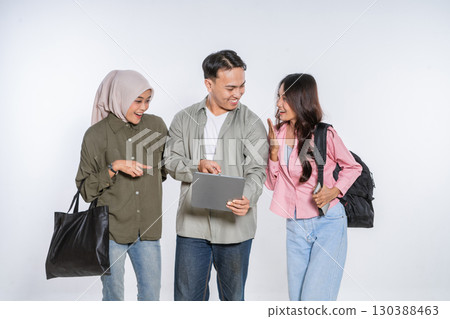 A group of friends joyfully enjoying their time outdoors with a tablet and backpacks 130388463