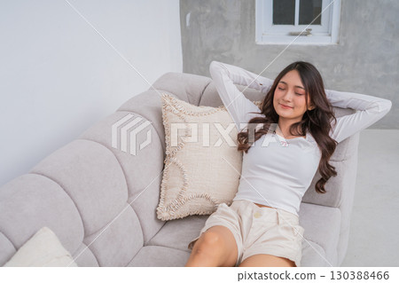 A Relaxed Young Woman Enjoying Leisure Time While Sitting Comfortably on a Cozy Couch A Relaxed Young Woman Enjoying Leisure Time While Sitting Comfortably on a Cozy Couch 130388466