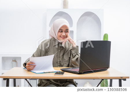 A Young Woman Actively Engaged in Online Learning with Her Laptop and Notes in Front A Young Woman Actively Engaged in Online Learning with Her Laptop and Notes in Front 130388506