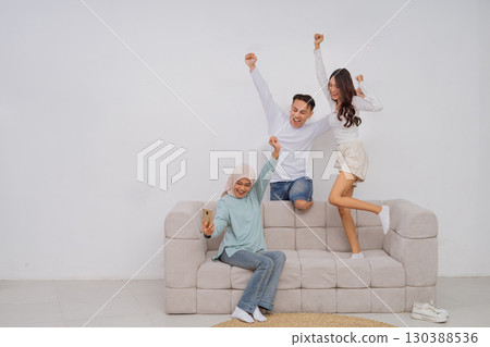 A joyful family celebration at home, gathered on a cozy sofa enjoying togetherness A joyful family celebration at home, gathered on a cozy sofa enjoying togetherness 130388536