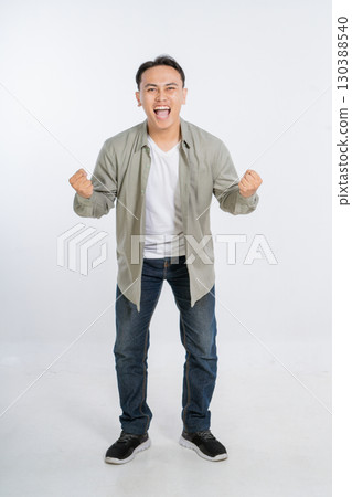 An Excited Young Man Joyfully Celebrating His Success with Energetic Fist Pumps 130388540