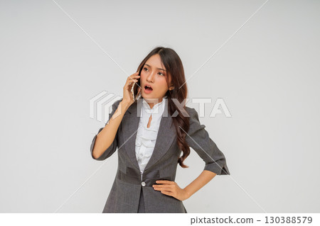 A shocked businesswoman dressed in professional attire speaks on the phone 130388579