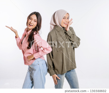 Stylish Women Posing Together in Trendy Outfits Against a White Background 130388602