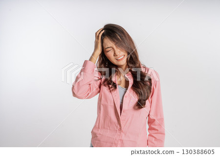 A young woman smiles in a casual pink outfit despite having a headache A young woman smiles in a casual pink outfit despite having a headache 130388605