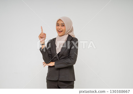 A Confident Businesswoman Dressed in a Stylish Suit with Hijab Pointing Upwards A Confident Businesswoman Dressed in a Stylish Suit with Hijab Pointing Upwards 130388667