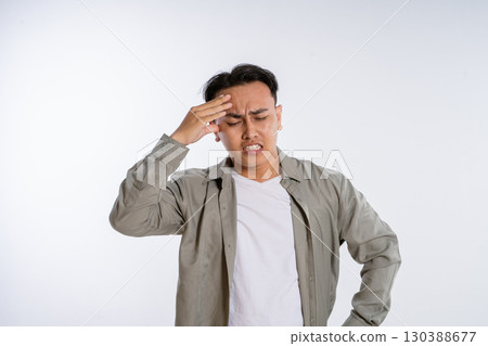 A Young Man in Casual Wear with a Stressful Expression and Headache on a Simple Background A Young Man in Casual Wear with a Stressful Expression and Headache on a Simple Background 130388677