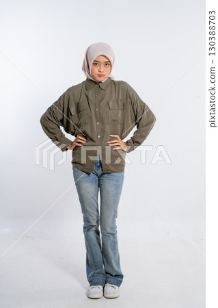 A Confident Young Woman in Casual Attire is Posing with Her Hands on Her Hips A Confident Young Woman in Casual Attire is Posing with Her Hands on Her Hips 130388703