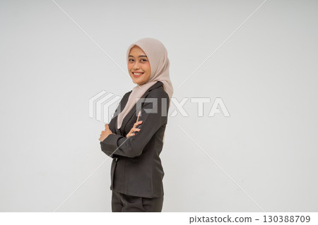 A confident young businesswoman dressed in professional attire, proudly wearing a hijab 130388709