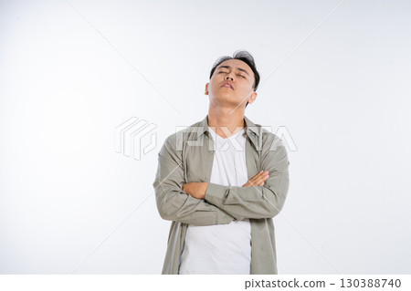 A Confident Young Man Standing with Arms Crossed, Posed Against a White Background 130388740