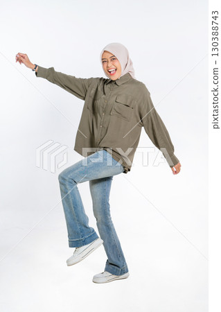 A Joyful Young Woman Expresses Her Happiness While Dancing in Casual Attire with a Hijab 130388743