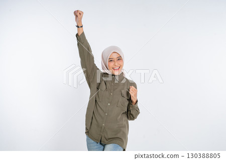 A Cheerful Young Woman Joyfully Celebrating Her Success with a Fist Pump Gesture A Cheerful Young Woman Joyfully Celebrating Her Success with a Fist Pump Gesture 130388805