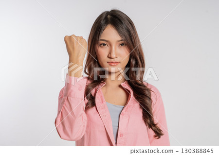 An Empowered Young Woman Raising Her Fist High in Determination and Strength 130388845