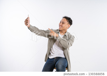 A Young Man Capturing a Selfie While Wearing a Happy and Joyful Expression 130388856