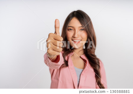 A Happy Young Woman is Joyfully Giving a Thumbs Up Gesture of Approval and Support 130388881