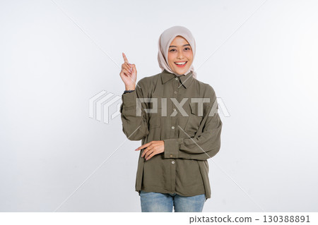 A Smiling Young Woman Dressed in a Hijab Pointing Upward on a White Background A Smiling Young Woman Dressed in a Hijab Pointing Upward on a White Background 130388891