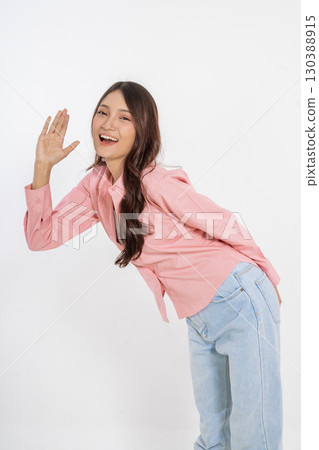 Cheerful Young Woman in Pink Top Posing and Waving Goodbye in Studio Setting Cheerful Young Woman in Pink Top Posing and Waving Goodbye in Studio Setting 130388915