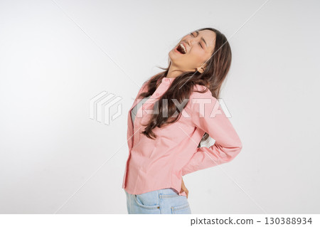 A Joyful Woman is Laughing Vibrantly in a Pink Shirt Set Against a White Background 130388934
