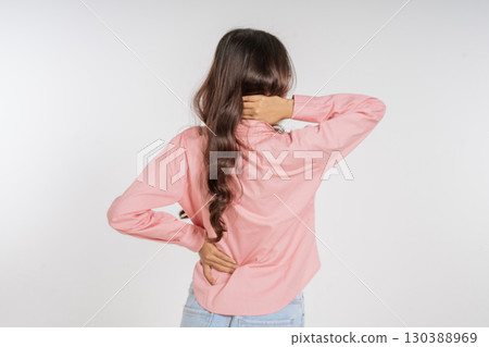 A Young Woman with Long Hair Holding Her Back While Dressed in Comfortable Attire A Young Woman with Long Hair Holding Her Back While Dressed in Comfortable Attire 130388969