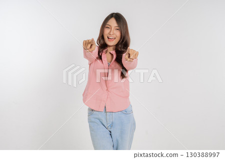 Cheerful Young Woman Posing Joyfully with Outstretched Arms Against White Background 130388997
