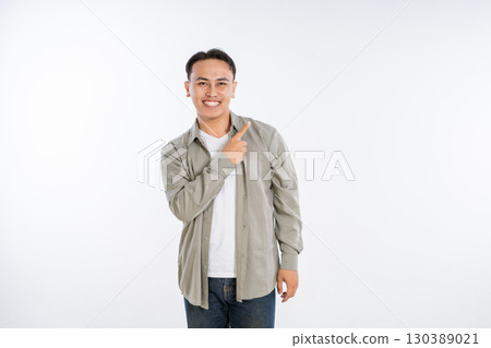 A cheerful young man confidently points with a bright smile, exuding positive energy A cheerful young man confidently points with a bright smile, exuding positive energy 130389021
