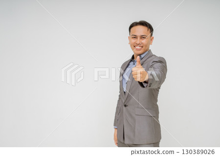 A Smiling Businessman Giving a Thumbs Up While Dressed in a Suit and Tie A Smiling Businessman Giving a Thumbs Up While Dressed in a Suit and Tie 130389026