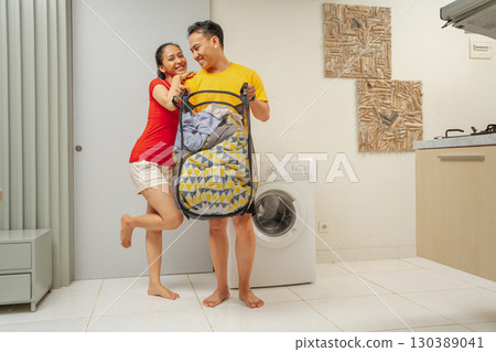 A Joyful Couple Enjoying Doing Laundry Together in the Comfort of Their Home 130389041