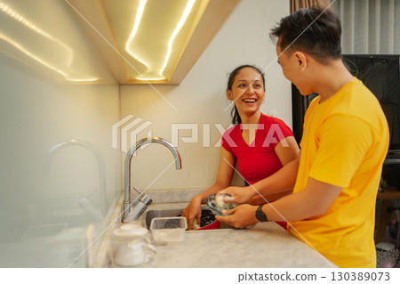 A couple happily enjoying their quality time together in a modern kitchen space 130389073