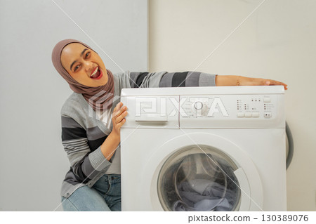 A Joyful Woman is Celebrating the Arrival of a New Washing Machine in Her Modern Home 130389076