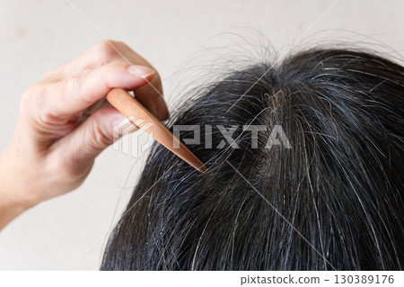 Close-up image of gray hair and flyaway hairs on the top of the head of a middle-aged woman Close-up image of gray hair and flyaway hairs on the top of the head of a middle-aged woman 130389176
