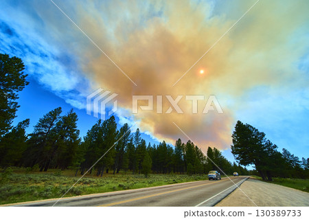 Forest Fire Smoke Plume Over Scenic Road and Pine Trees with Sun in Rural Utah 130389733