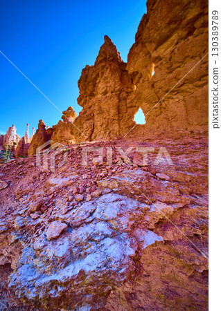 Bryce Canyon Hoodoo Formations and Arch with Rocky Foreground Under Blue Sky 130389789