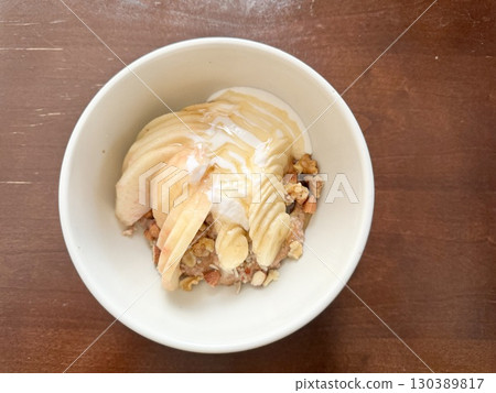 Stock Photo: Oatmeal bowl topped with peaches, bananas and nuts (breakfast) 130389817
