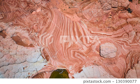 Aerial Swirling Sandstone Layers and Erosion Patterns with Desert Pool Top Down Aerial Swirling Sandstone Layers and Erosion Patterns with Desert Pool Top Down 130390077