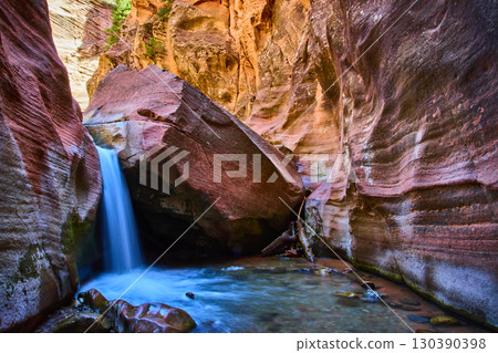 Waterfall Motion Over Angular Boulder in Striated Sandstone Canyon Eye Level View 130390398