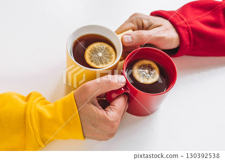 friends share warm cups lemon tea while enjoying cozy afternoon at home during fall season. closeup. friends share warm cups lemon tea while enjoying cozy afternoon at home during fall season. closeup. 130392538