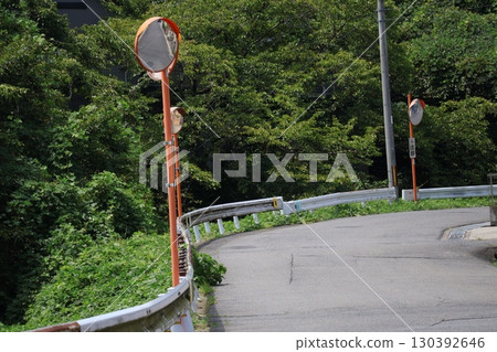 A winding road with many convex mirrors and a townscape with green trees 130392646