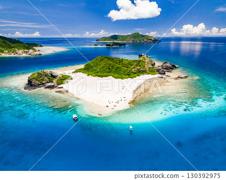 無人機拍攝的卡比島。遊客們在白色沙灘上。遮陽傘、船隻和薩巴尼船停泊在那裡。 130392975