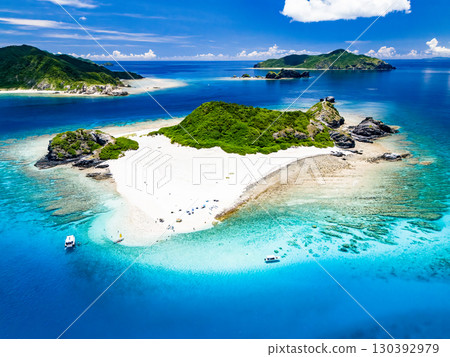 無人機拍攝的卡比島。遊客們在白色沙灘上。遮陽傘、船隻和薩巴尼船停泊在那裡。 130392979