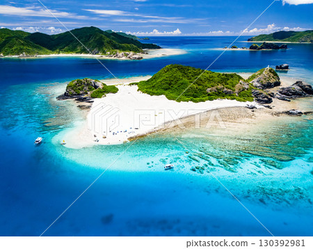 Drone shot of Kabi Island. Tourists are on the white sand beach. Parasols, boats, and sabani boats are moored. Drone shot of Kabi Island. Tourists are on the white sand beach. Parasols, boats, and sabani boats are moored. 130392981