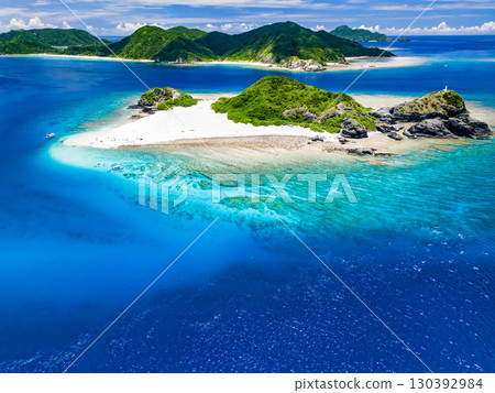 Drone shot of Kabi Island. Tourists are on the white sand beach. Parasols, boats, and sabani boats are moored. 130392984