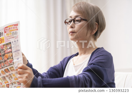 Senior woman looking at supermarket flyers Senior woman looking at supermarket flyers 130393223
