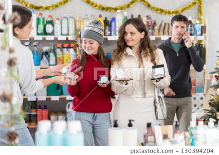 Woman seller offers cosmetics to mother and daughter Woman seller offers cosmetics to mother and daughter 130394204