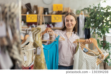 Girl chooses a set of clothes for summer. Visitor to the boutique examines the new summer collection of clothes 130394208