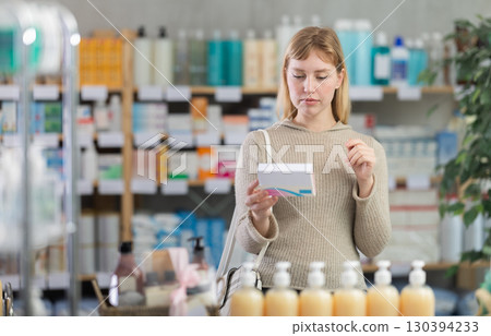 Young woman chooses pills at pharmacy Young woman chooses pills at pharmacy 130394233