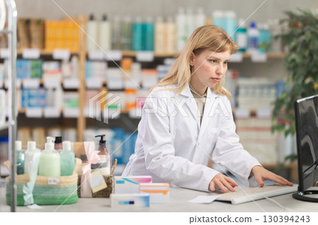 Female pharmacist working at a computer Female pharmacist working at a computer 130394243