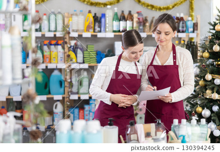 Woman seller with teen daughter, using paper report make inventory in household chemistry store Woman seller with teen daughter, using paper report make inventory in household chemistry store 130394245