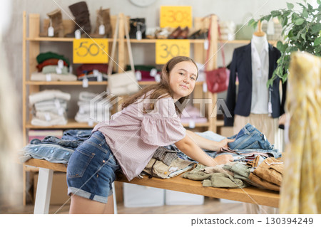 Teenage girl choosing jeans in clothing store 130394249