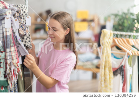 Teenage girl choosing some scarf in clothing store 130394259