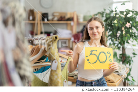 Teen girl holding discount sign in clothing store 130394264