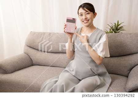 懷孕八個月的女子坐在沙發上，手上拿著計算機 130394292